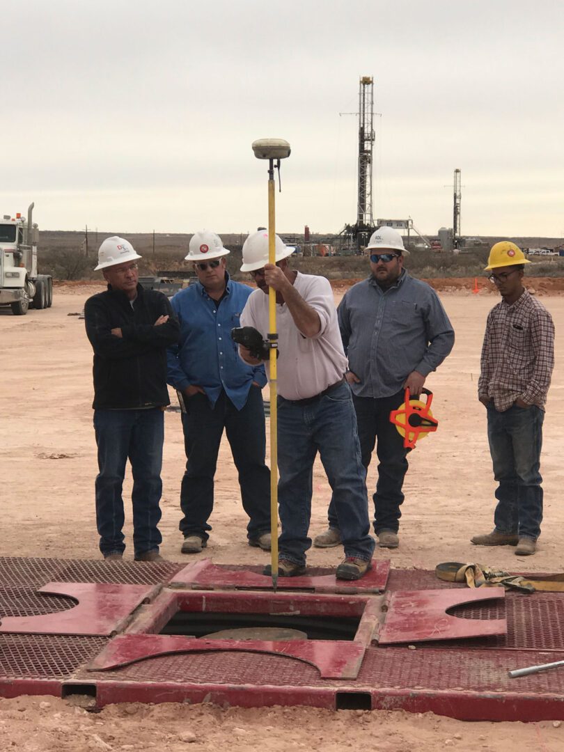 A group of men standing around a hole.