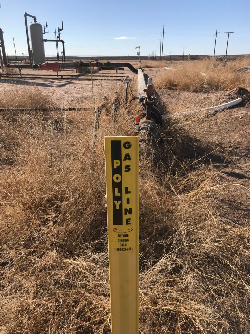 A yellow pole with a sign on it in the middle of an empty field.